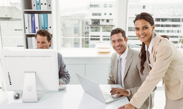 Bedrijfsmensen die laptop en computer in bureau met behulp van