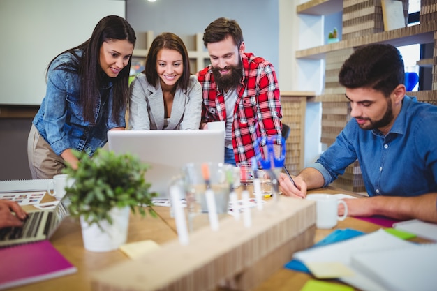 Bedrijfsmensen die over laptop bij bureau bespreken