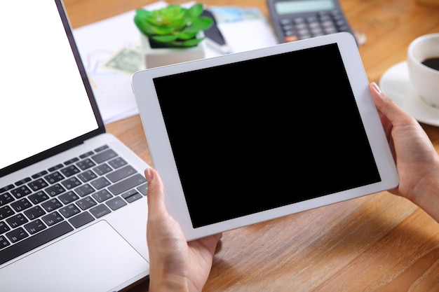 Bedrijfsmensen die tabletmodel met laptopmodel en kantoorbenodigdheden houten bureau houden