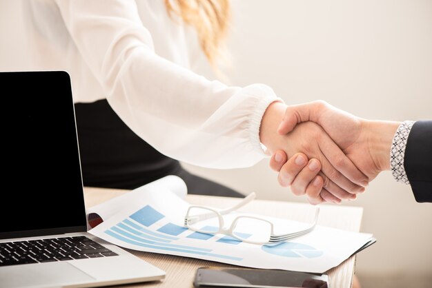 Foto bedrijfsmensenhanddruk na ondertekening van het partnerschapscontract op kantoor naast bureau