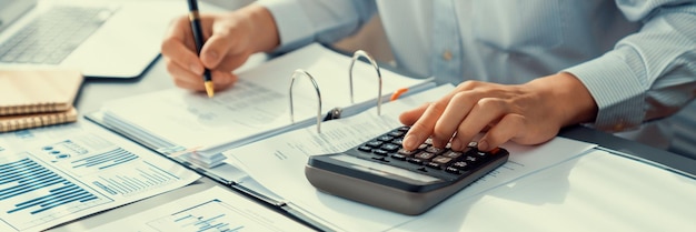 Bedrijfsrevisor die budget berekent met rekenmachine op zijn bureau Toegewijde accountantprofessional van boekhoudbedrijf die financieel document analyseert om inkomensinzicht te voorspellen