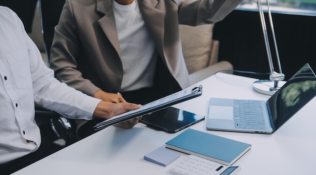 Bedrijfsteam werkt met een nieuw startprojectplan en bespreekt informatie voor financiële strategie met een laptop en een digitale tablet in een moderne zakelijke lounge