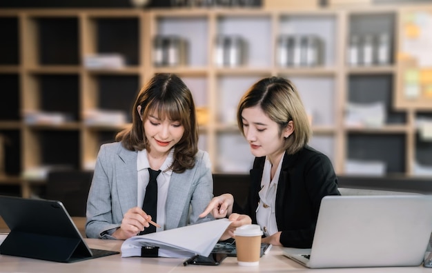 Bedrijfstechnologie en kantoorconcept twee zakenvrouwen met laptop tablet pc-computer en papieren die discussie hebben in een modern kantoor