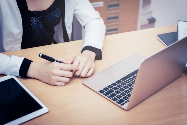 Bedrijfsvrouw die laptop in bedrijfskantoor met kantoor gebruiken