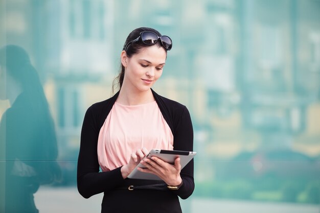 Bedrijfsvrouw die met de tablet in openlucht dichtbij het bureau werken