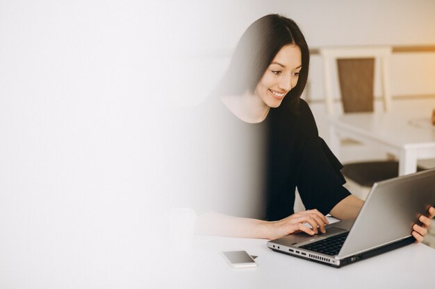 Bedrijfsvrouw die met laptop in een witte koffie werken