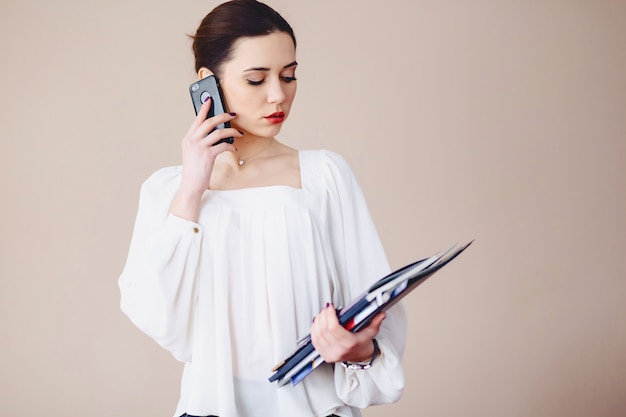 Bedrijfsvrouw die op telefoon met documenten in haar handen spreken