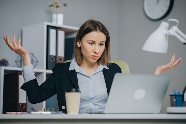 Bedrijfsvrouw die slecht nieuws op laptop computer lezen bij coworking ruimte. verstoorde vrouw die laptop in bureau sluit. moe vrouw ademen diep op de werkplek.