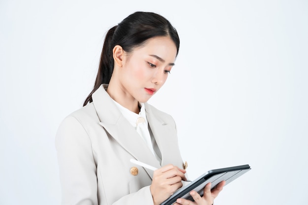 Bedrijfsvrouw in grijs kostuum die tablet en pen gebruiken om de notulen van vergadering en het werk te registreren.