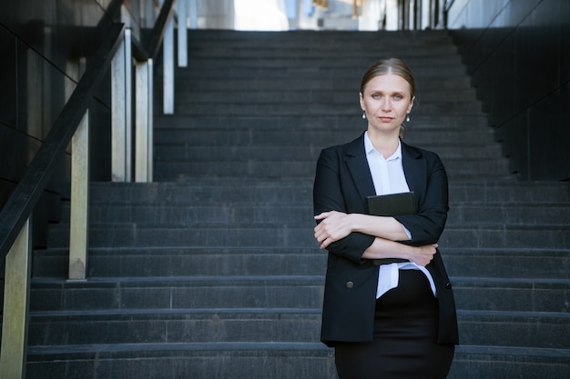 Bedrijfsvrouw met in hand blocnote in zwarte verbindingsdraad op de treden