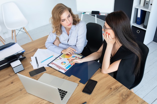 Bedrijfsvrouwen die bij bureau aan laptop, groepswerkconcept samenwerken