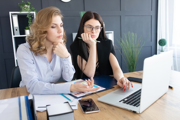 Bedrijfsvrouwen die bij bureau aan laptop, groepswerkconcept samenwerken