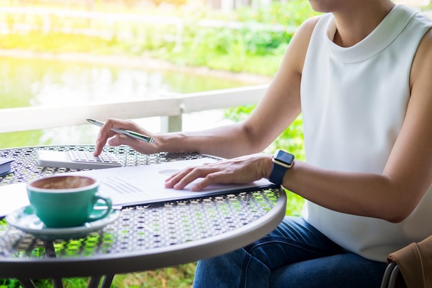 Bedrijfsvrouwen die door calculator voor proces financieel rapport in de tuin werken te werken