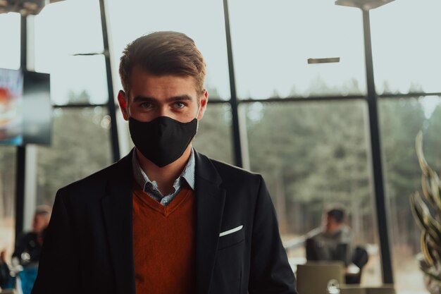 bedrijfszakenman die een beschermend medisch gezichtsmasker draagt bij modern open ruimtebureauconcept nieuw normaal in zaken