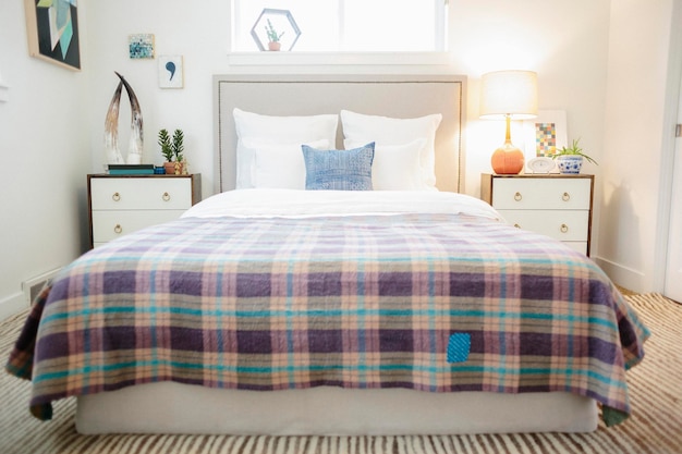 A bedroom in an apartment double bed covered with a checked purple and cream bed cover