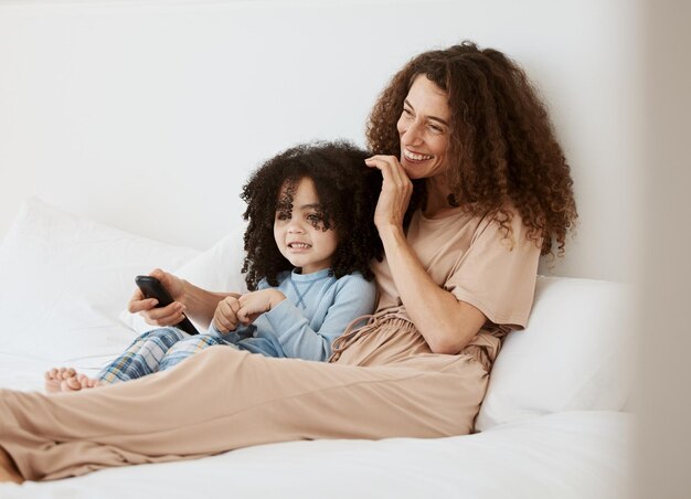 Bedroom happy family child and mother watching tv series movie or streaming online video cinema or entertainment Home bed kids and relax woman mom or mama watch cartoon show television or film