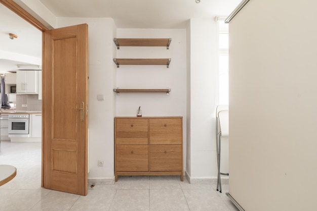 The bedroom has a chest of drawers with four wooden drawers and three matching wall shelves