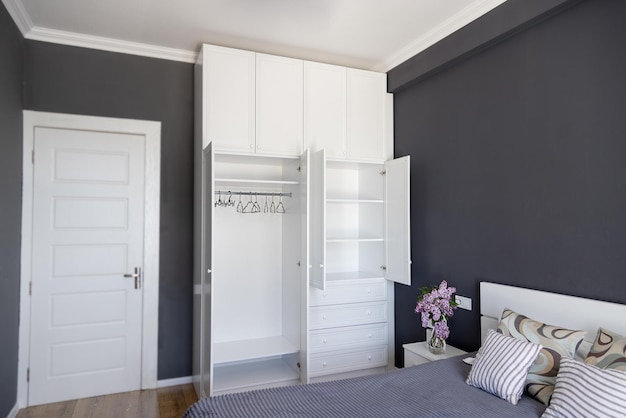 Bedroom interior with empty white wardrobe against gray walls Modern interior