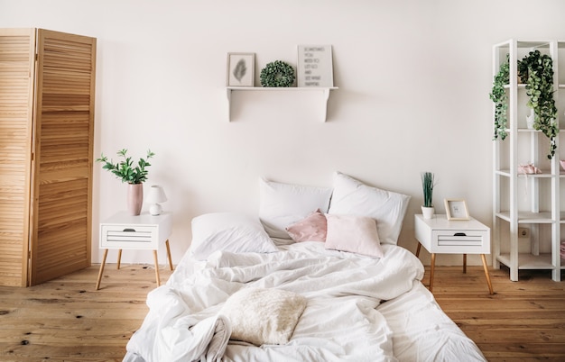 Bedroom is bright and comfortable with a large bed and white wooden furniture and floral green decor