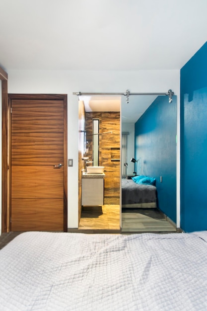 Bedroom room in the background you can see a bathroom with mirrored sliding door wooden door