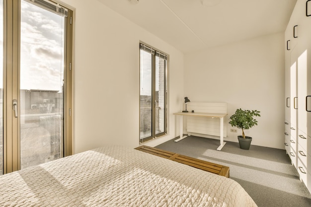 A bedroom with a bed and a desk and windows