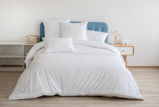 Photo bedroom with bed, white bedding, and bedside table.