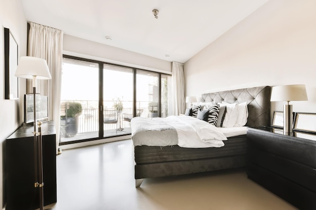 A bedroom with a black bed and a large window