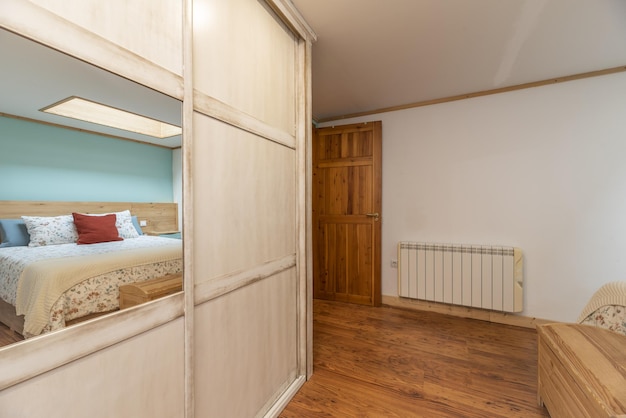 Bedroom with a double bed with a wardrobe with white sliding doors and mirrors and dark wooden floors