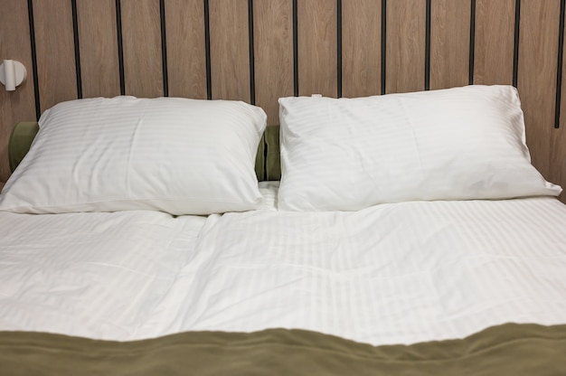 Bedroom with made bed in a warm colors. queen size comfortable\
bed with two pillows and windows in the room. made bed in the\
hotel. the clean bedclothes, pillows, bed sheet and blanket in a\
room