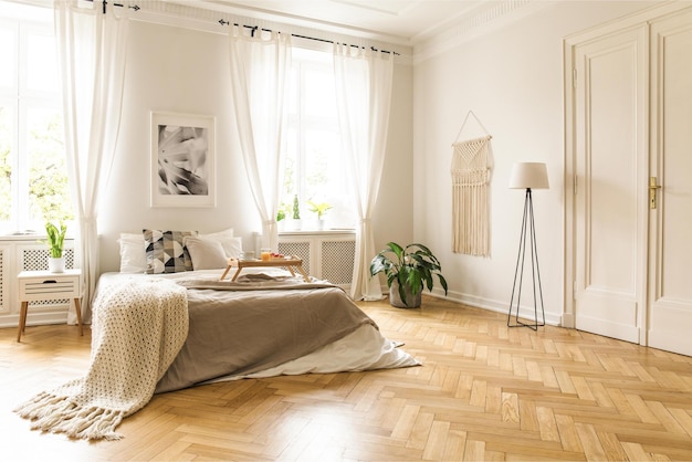 A bedroom with a white floor and white walls and a large window with a picture of a bed and a lamp.