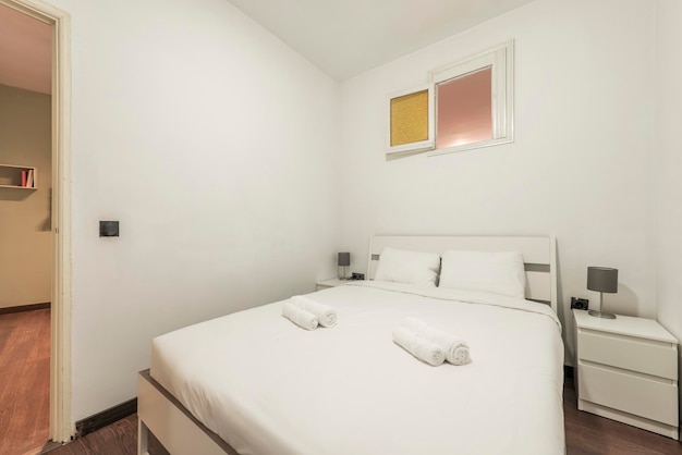 Bedroom with white wooden bed with white duvet and matching nightstands with drawers