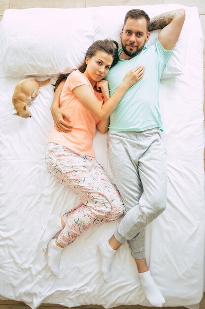 Bedtime. The family are sleeping. Beautiful young couple in love are lying on the big white bed and resting. Husband and wife together in bed. Top view photo