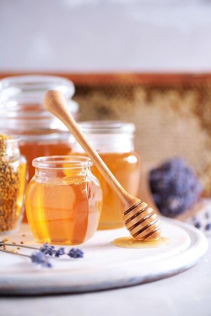 Bee pollen granules honey jar with wooden dropper honeycomb on grey backdrop copy space autumn harvest concept