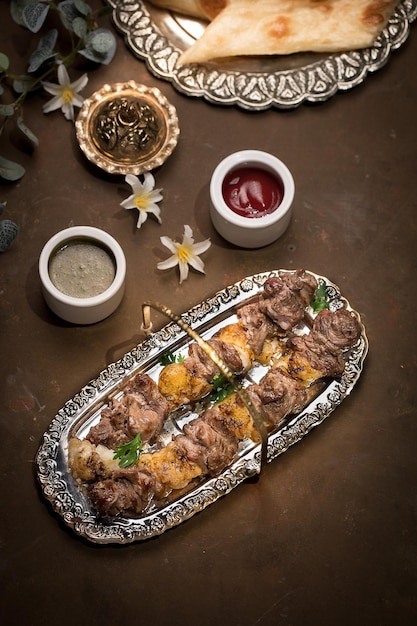 Beef Afghani Tikka Boti Kebab paltter met raita en ketchup geserveerd in schotel geïsoleerd op donkere achtergrond bovenaanzicht