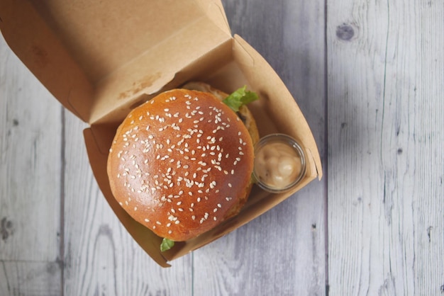 beef burger and french fries in a takeaway paper box on table