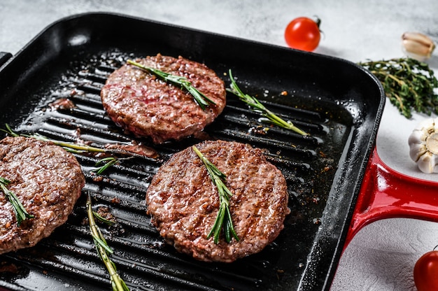 Beef burger patties sizzling on a hot barbecue pan. Top view