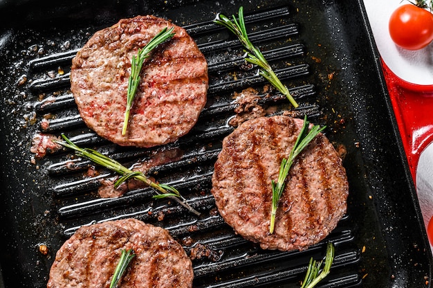 Beef burger patties sizzling on a hot barbecue pan. Top view