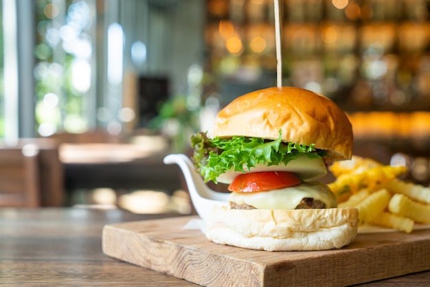 beef burger with cheese and potato chips on wood tray