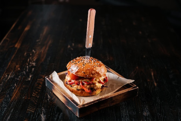 Beef burger with knife on wooden table