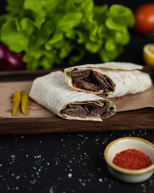 A beef burrito with a side of red pepper and a bowl of red pepper.