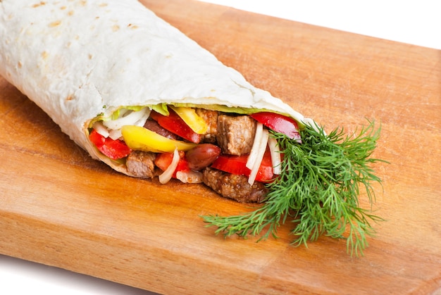 Beef burrito with yellow and red peppers, onion and tomato on plate