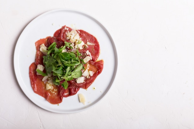 Beef carpaccio with arugula and sauce. Top view