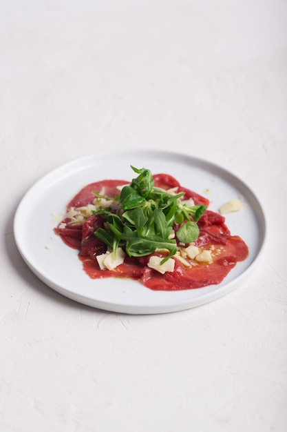 Beef carpaccio with arugula and sauce. Vertical orientation