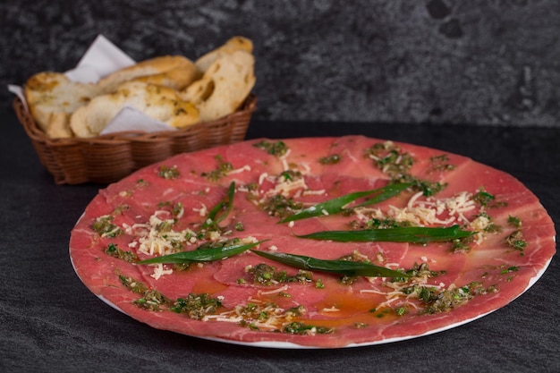 Foto carpaccio di manzo con cesto di pane tostato