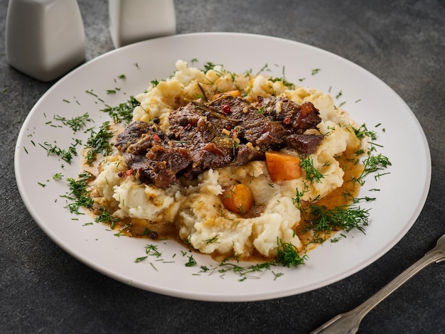 Guance di manzo con purè di patate su piatto bianco