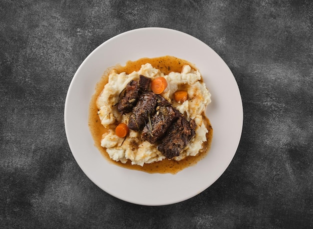 Beef cheeks with mashed potatoes on white plate