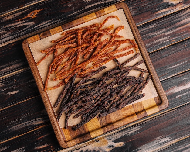 Beef and chiken jerky on wooden board