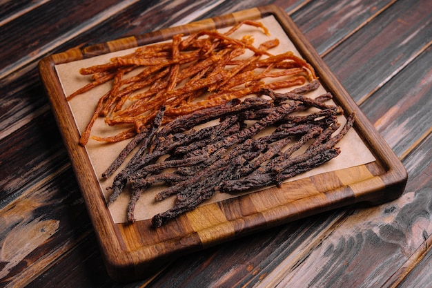 Beef and chiken jerky on wooden board