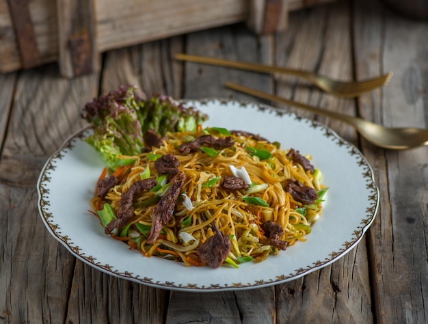 Beef chinese noodles served in a dish isolated on wooden background side view of noodles