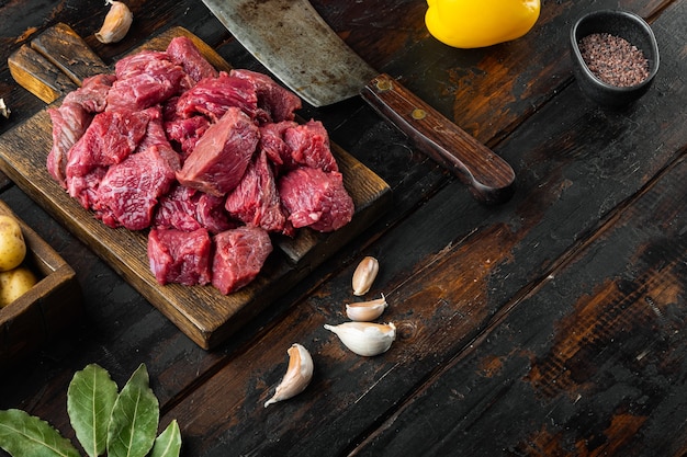 Набор ингредиентов для тушеного мяса из говяжьей вырезки на старом темном деревянном столе с местом для текста
